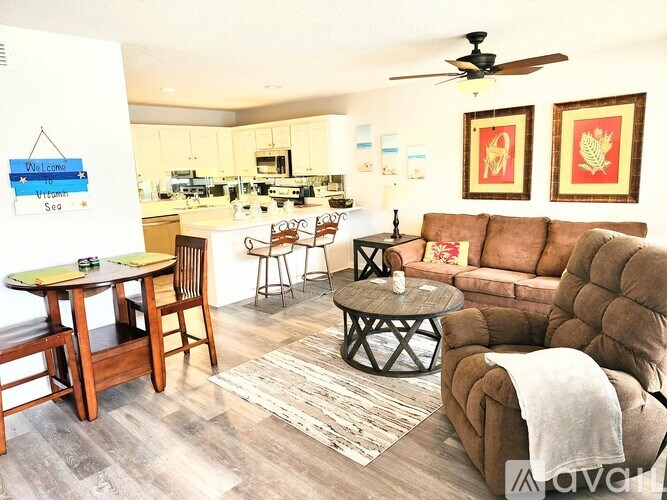 A living room with a brown couch, a round table, and a ceiling fan.