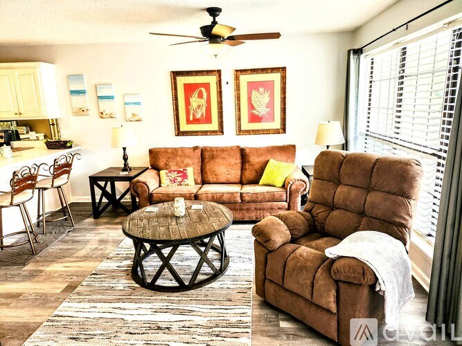 A living room with brown furniture and a ceiling fan.