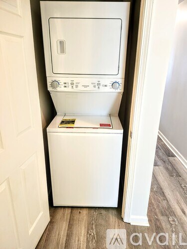 A white washing machine is in a small space between a door and a wall.
