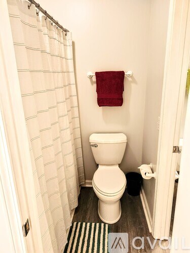 A white toilet in a small bathroom with a red towel hanging on the wall.