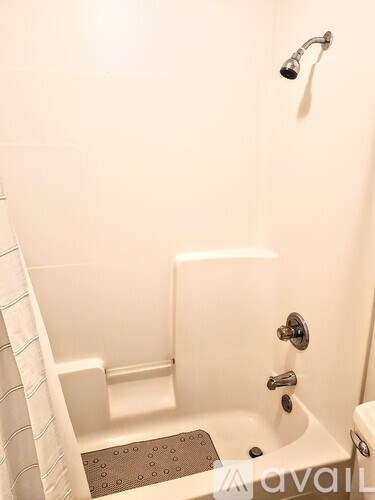 A white bathtub with a shower head and a towel rack.