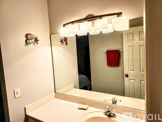 A bathroom with a white counter and a mirror reflecting a red object.