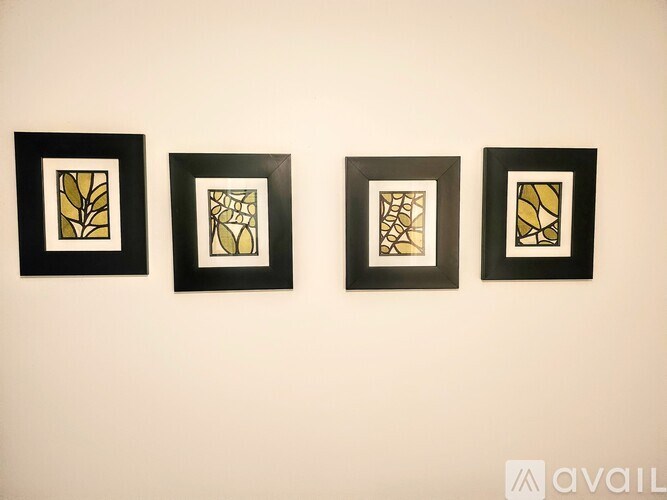 Four framed pieces of artwork are lined up on a wall.
