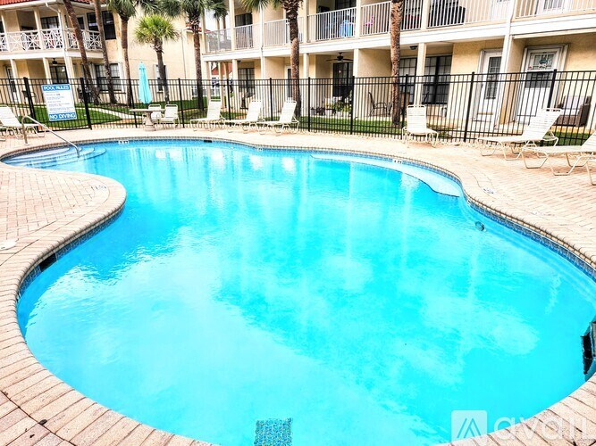 A small pool surrounded by a black fence and chairs.