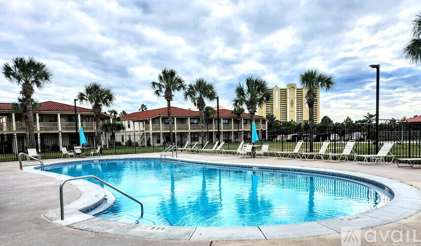 A large swimming pool surrounded by lounge chairs and palm trees.