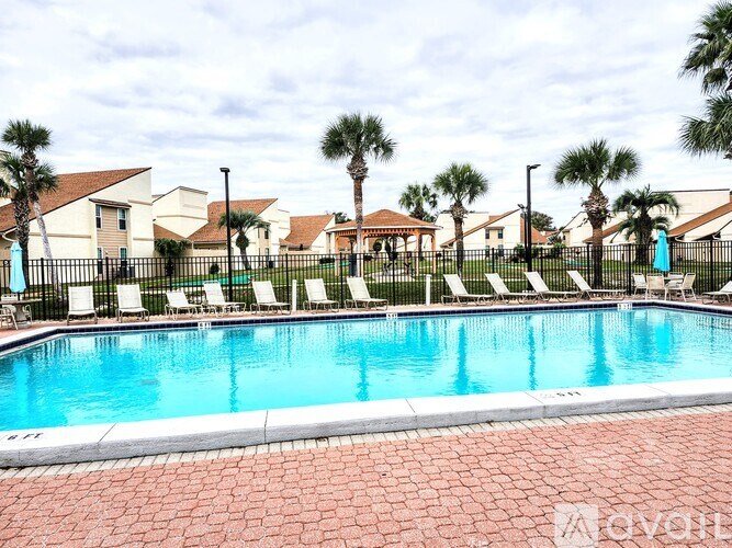 A pool surrounded by palm trees and lounge chairs.
