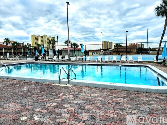 A pool with a brick floor and a metal ladder.