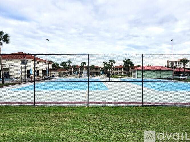 A pool surrounded by a fence with a grassy area in front.