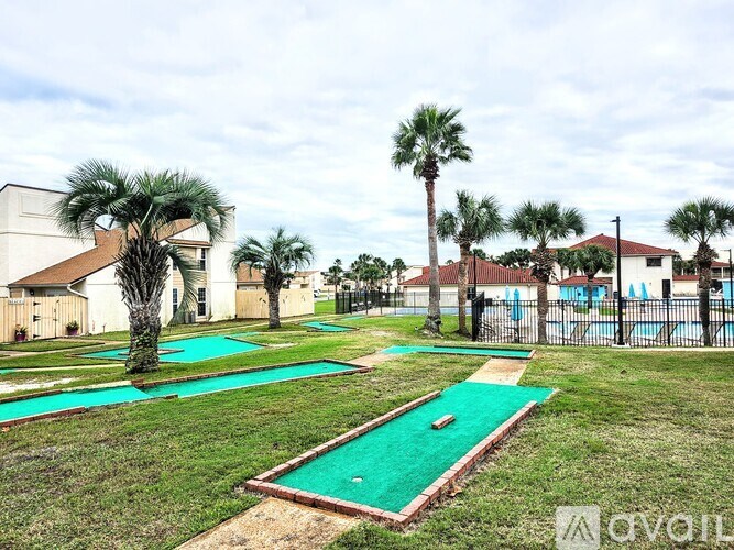 A miniature golf course with a green putting mat and a palm tree.
