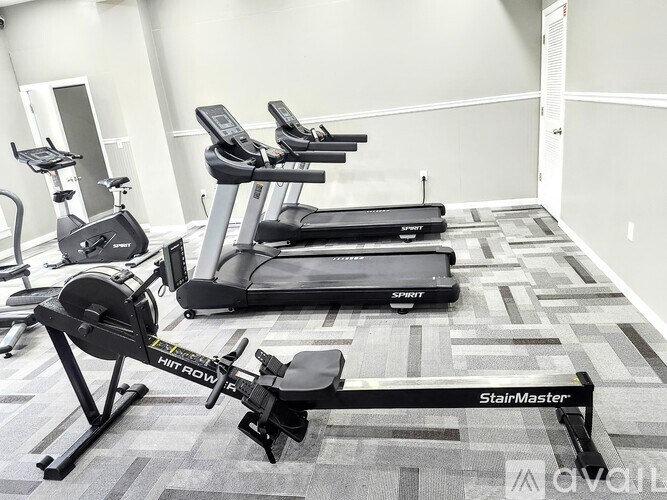 A gym with a row of treadmills and a row of stationary bikes.