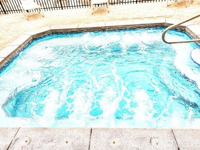 A hot tub with blue water and a metal handle.