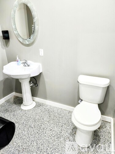 A white toilet sits next to a white pedestal sink in a bathroom.