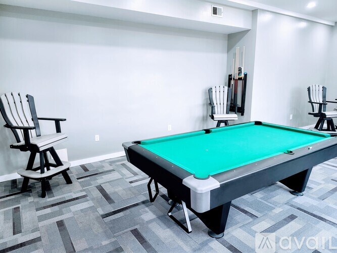 A pool table with a green cloth and two chairs.