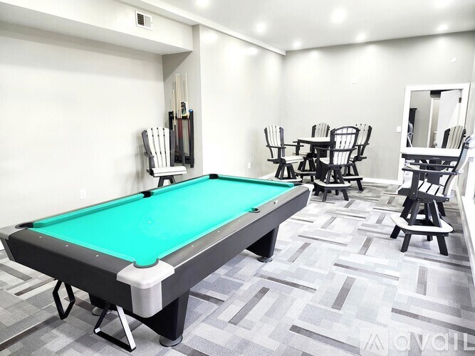 A pool table is surrounded by eight chairs in a room.
