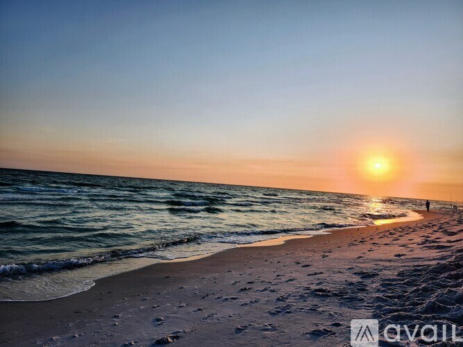 A beach scene with the sun setting over the ocean.