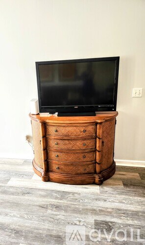 A black television sits on top of a wooden chest of drawers.