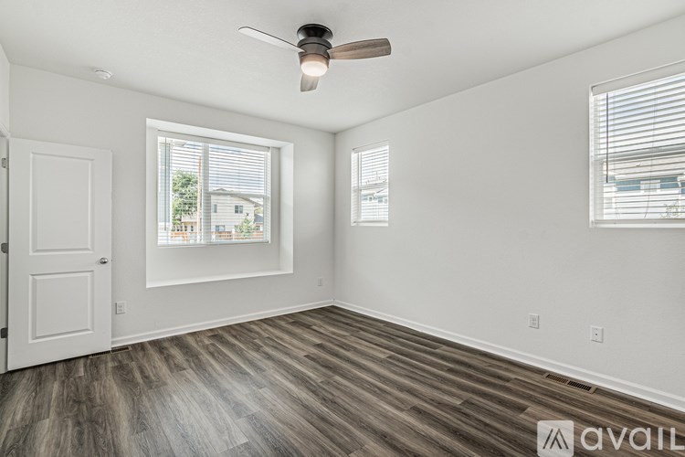 A room with a ceiling fan and two windows.