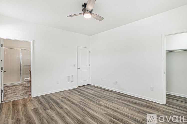 A room with a ceiling fan and wooden flooring.