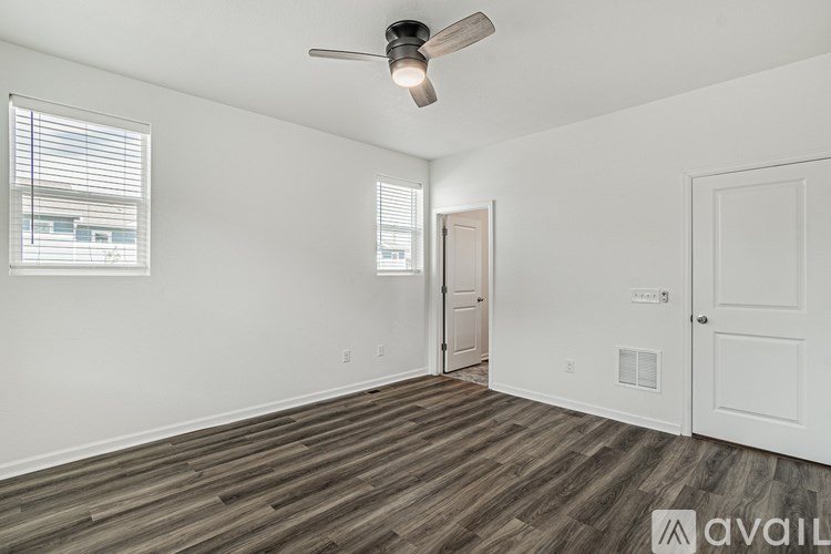 A room with a ceiling fan and wooden flooring.