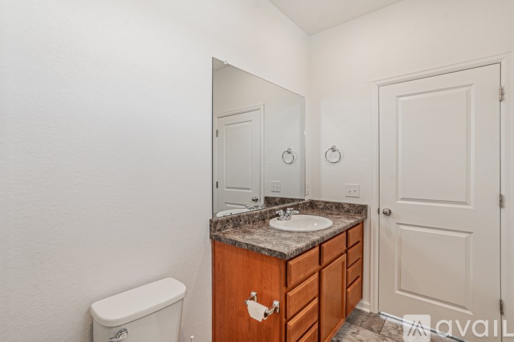 A bathroom with a toilet, sink, and mirror.