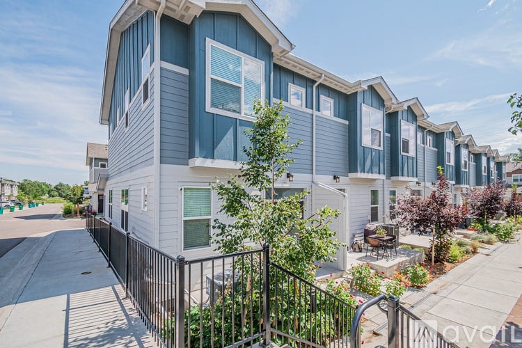A row of townhouses with a black fence in front.