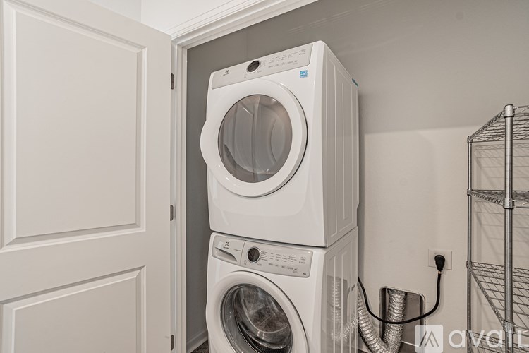 A white washing machine is stacked on top of another white washing machine in a small laundry room.