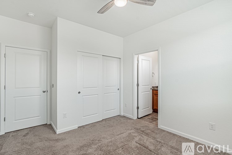 A room with a carpeted floor and a ceiling fan.