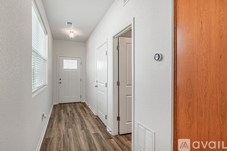 A hallway with a wooden floor and white walls.