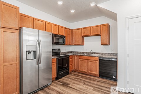 A kitchen with wooden cabinets and a stainless steel refrigerator.