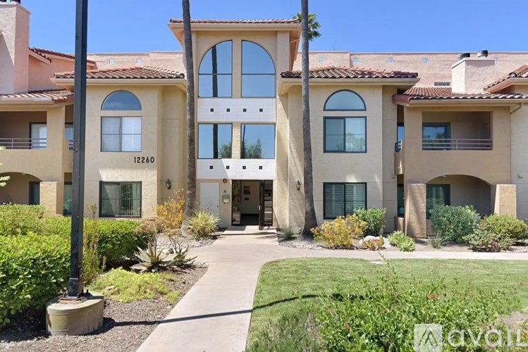 A large house with a balcony and a driveway in front.