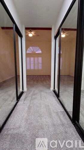 A hallway with a carpeted floor and a mirror on the wall.