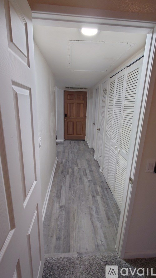 A hallway with white walls and wood flooring.