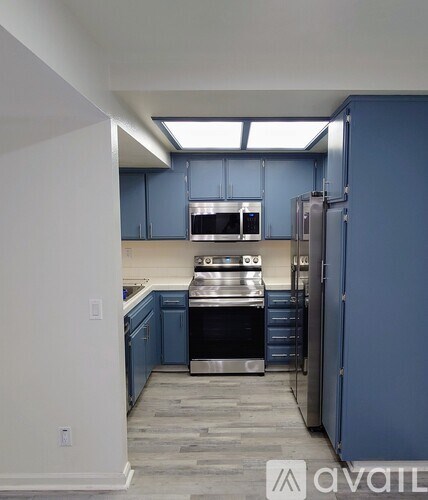 A kitchen with blue cabinets and stainless steel appliances.