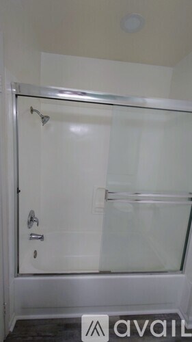 A shower stall with a glass door and a white tub.