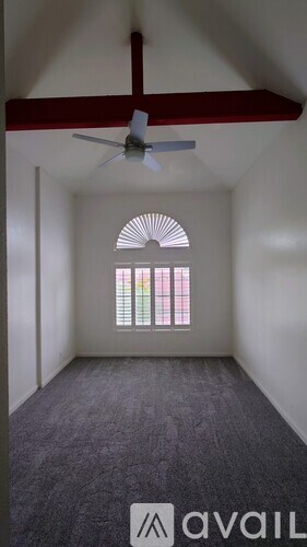 A room with a ceiling fan and a window with a view of a colorful building.
