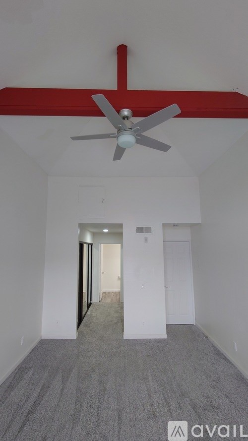 A room with a ceiling fan and a red beam.