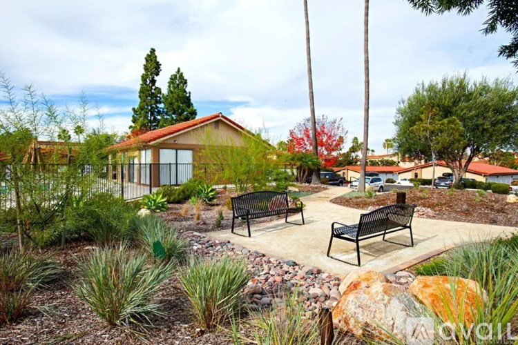 A park with benches and a building in the background.