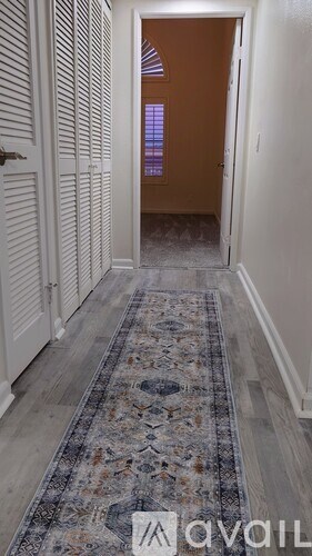 A hallway with a rug and a door at the end.
