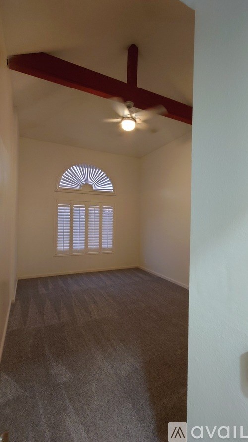 A room with a ceiling fan and a window with blinds.