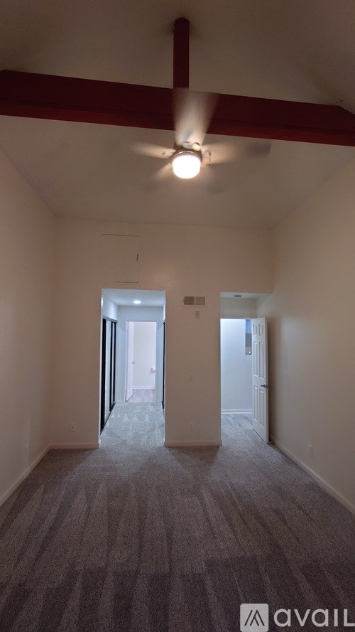 A room with a carpeted floor and a ceiling fan.