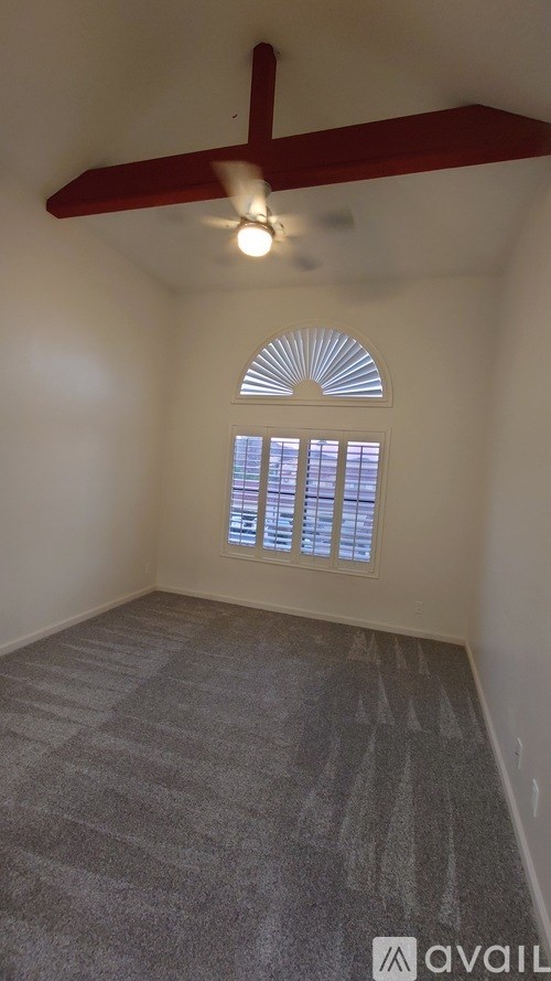 A room with a ceiling fan and a window with blinds.