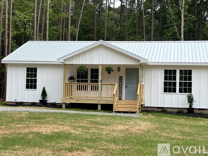 A small white house with a porch and a metal roof.