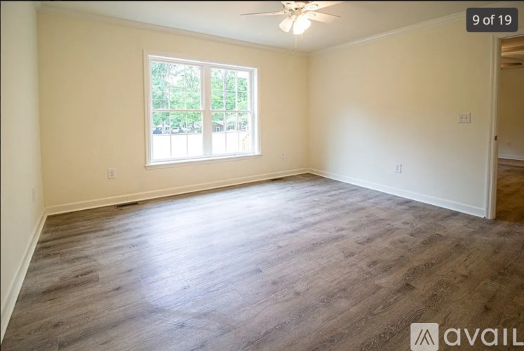A room with wooden flooring and a window with blinds.