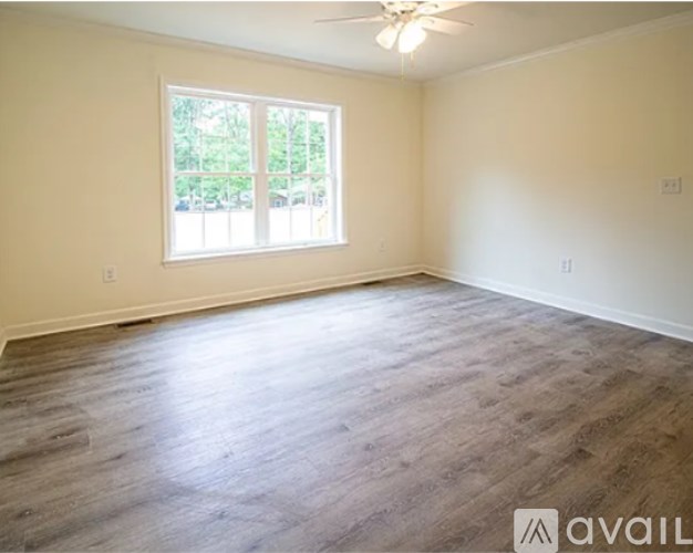 A spacious room with a window and wooden flooring.