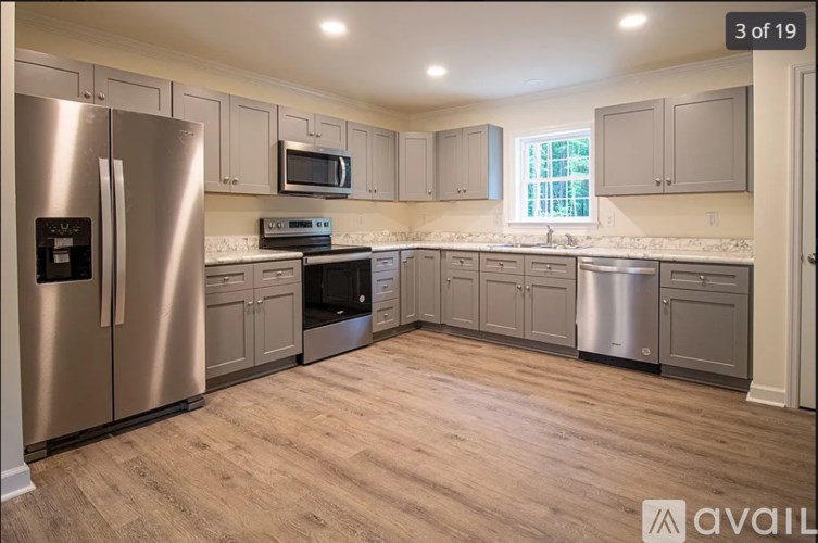 A kitchen with a stainless steel refrigerator and wooden flooring.