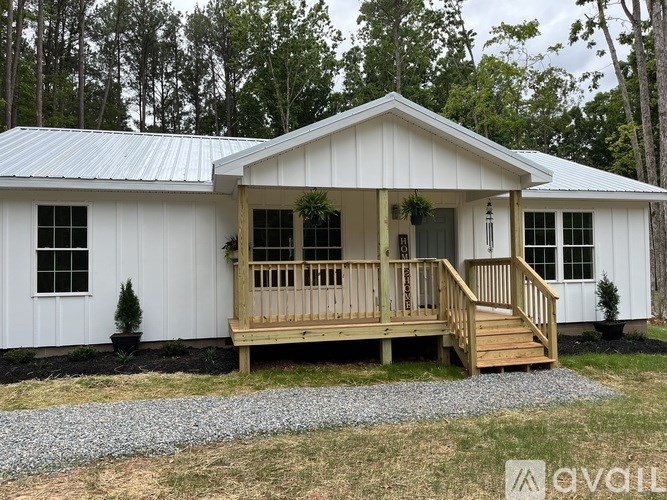 A small white house with a porch and a metal roof.