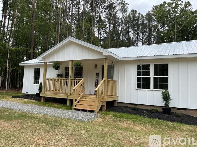 A small white cabin with a porch and a metal roof.