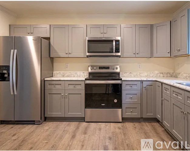 A kitchen with a stainless steel refrigerator and a microwave above the stove.