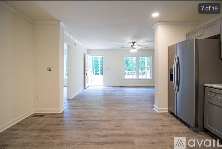 A spacious kitchen with a refrigerator, cabinets, and a window with a view of trees.