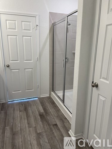 A white door with a glass shower stall in the bathroom.